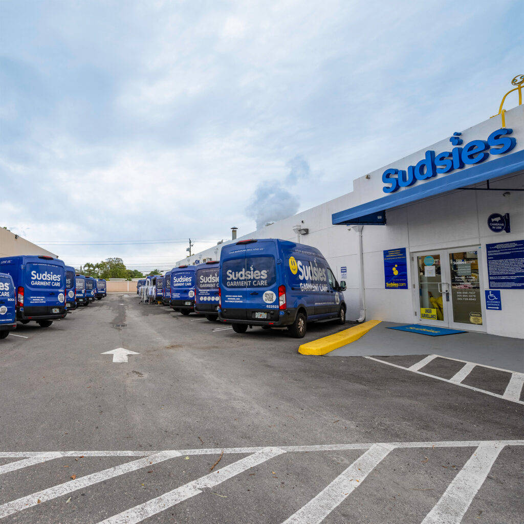 Sudsies garment care facility with branded delivery vans parked outside