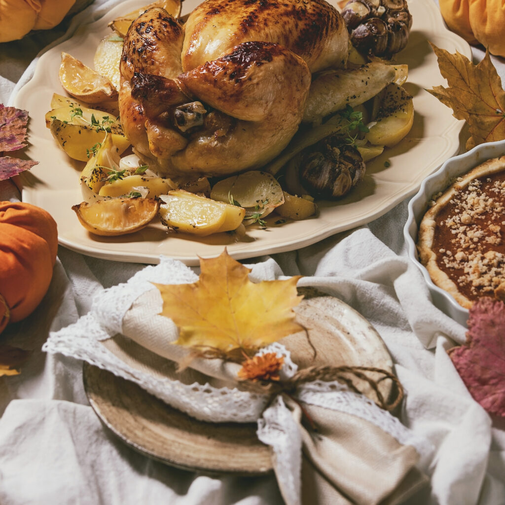 Holiday table setting with roasted chicken, pumpkins, and decorative linens, representing seasonal linens that need professional cleaning.