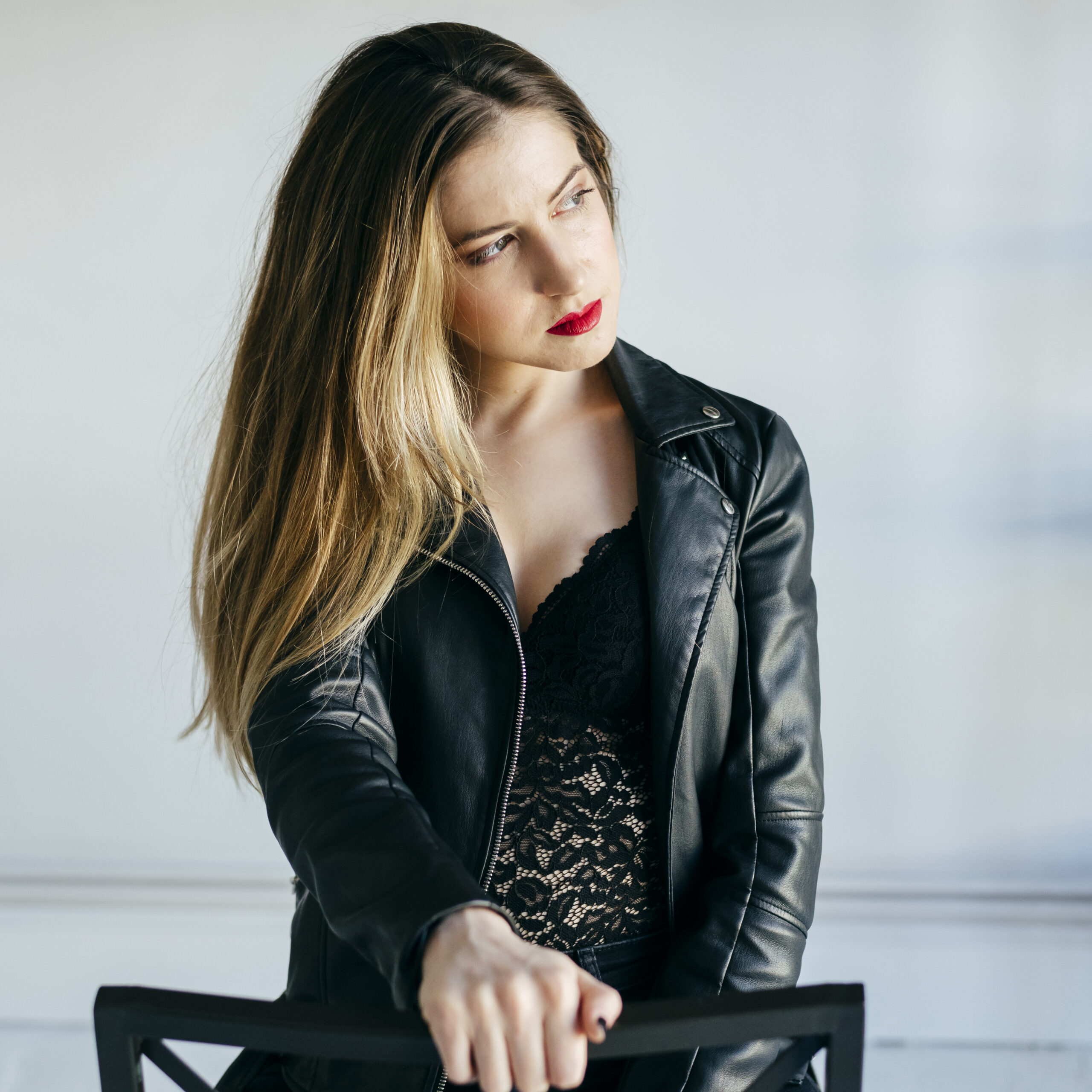 Stylish woman in a black leather jacket and lace top, perfecting winter fashion with confidence