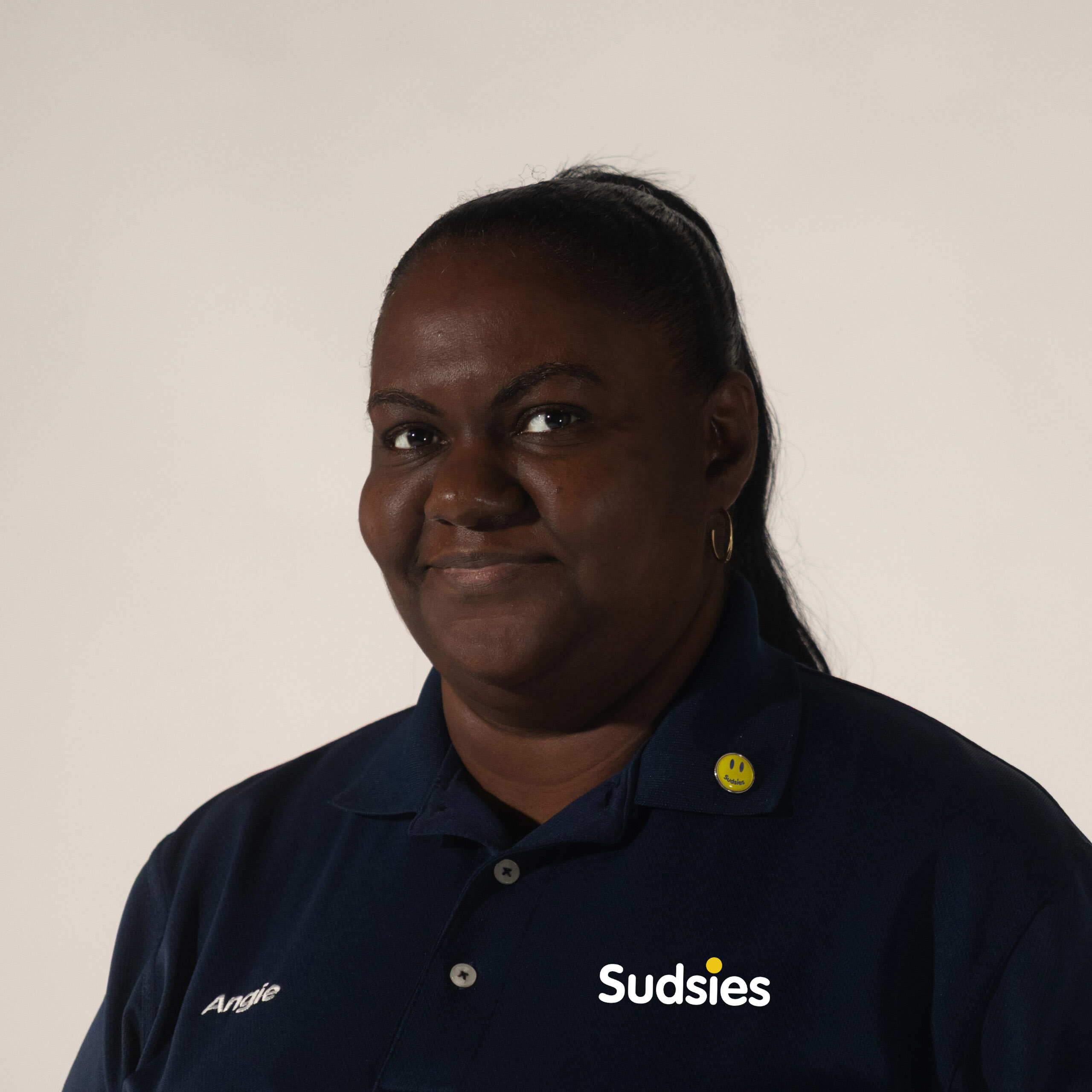 Angie Charles wearing a Sudsies Couture uniform, smiling during a staff portrait