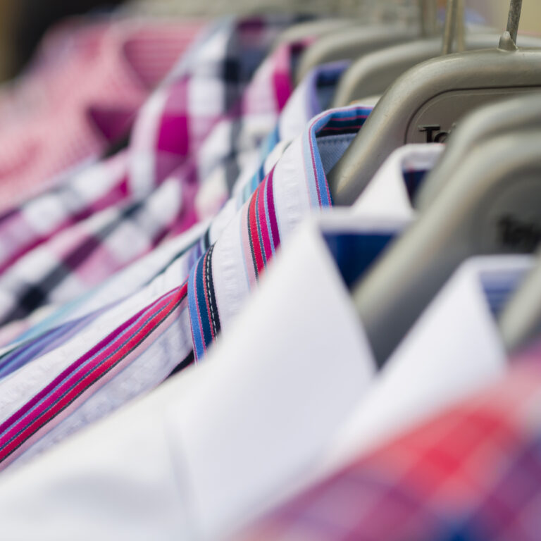 Close-up of colorful men’s dress shirts on hangers at Sudsies dry cleaning boutique