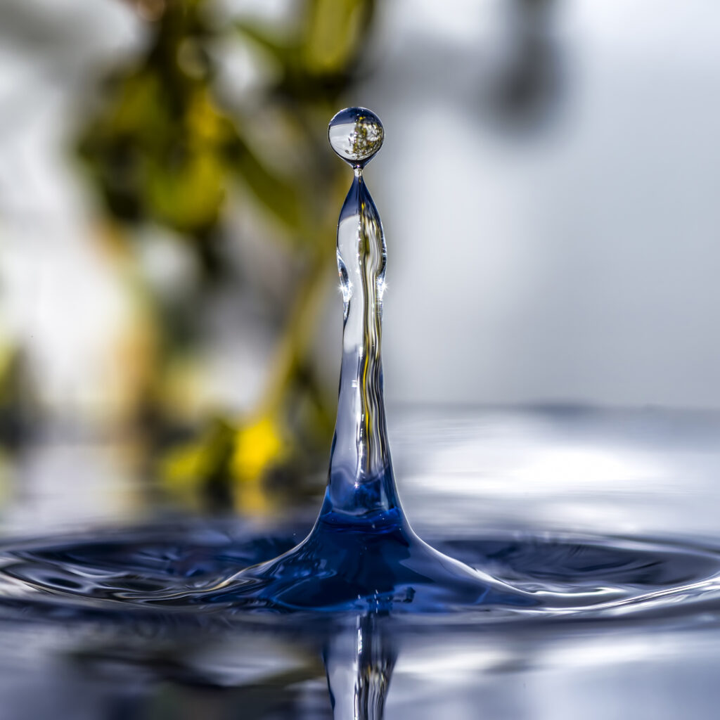 High-speed photo of a water droplet rising from a still surface, symbolizing Sudsies' eco-friendly wet cleaning technology