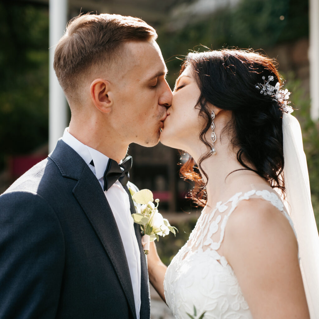 Bride and groom kiss on wedding day in outdoor garden ceremony