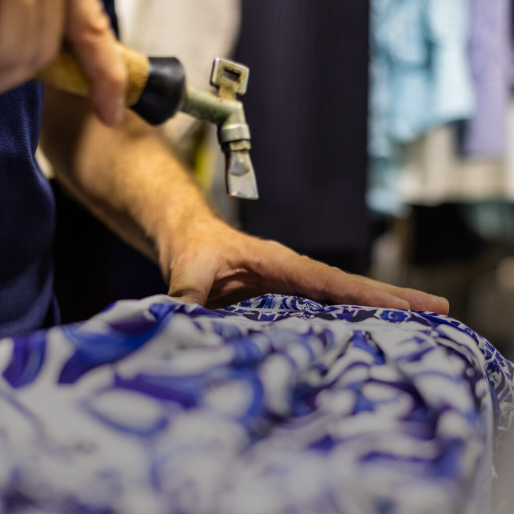 Garment care specialist using a steam gun during spot cleaning on patterned fabric