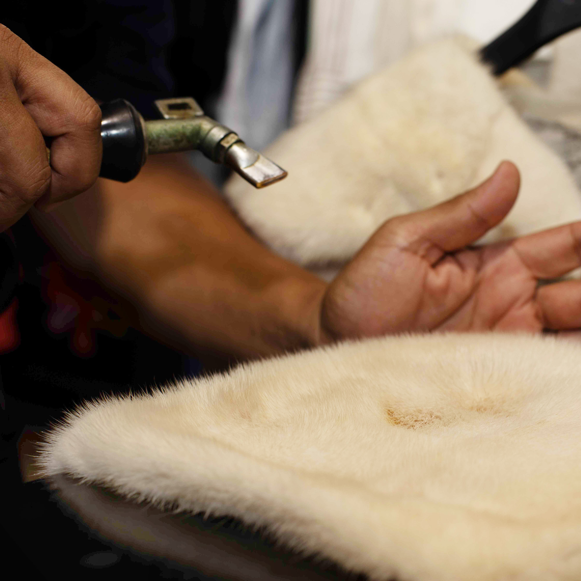 Garment care specialist using a steam gun to treat a stain on a fur garment