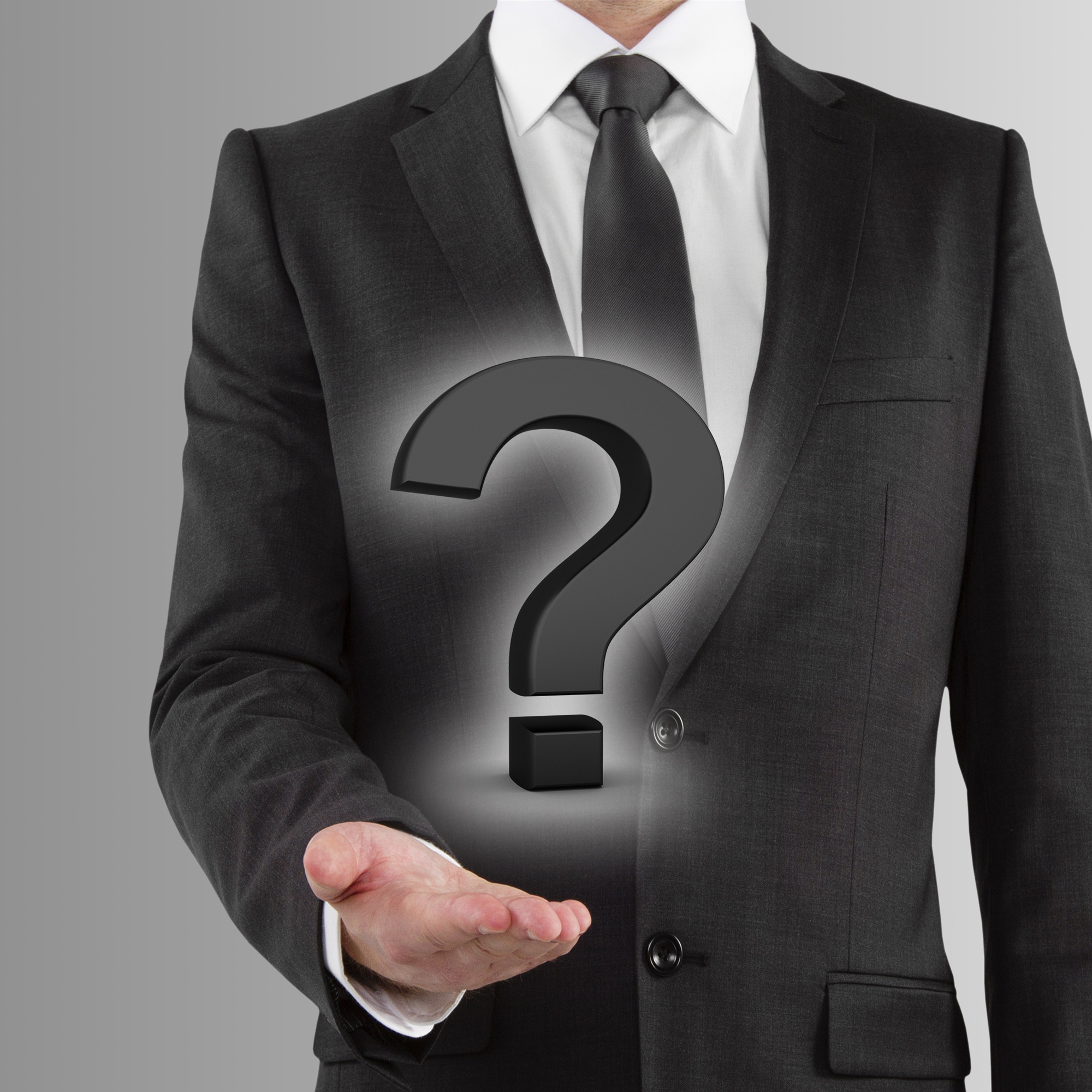 Person in a dark suit holding a floating question mark symbol