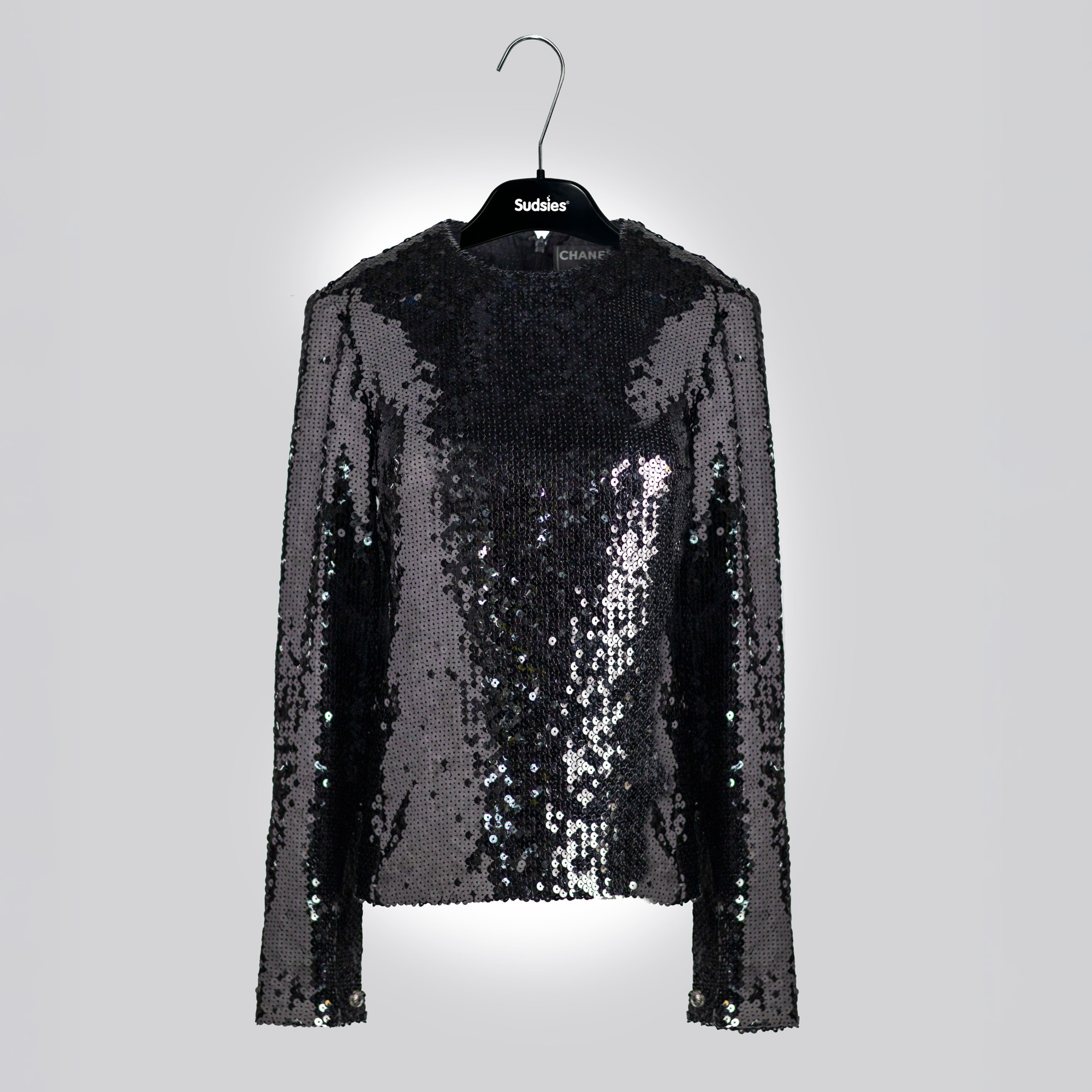 Black sequin long-sleeve top hanging on a Sudsies hanger against a neutral background
