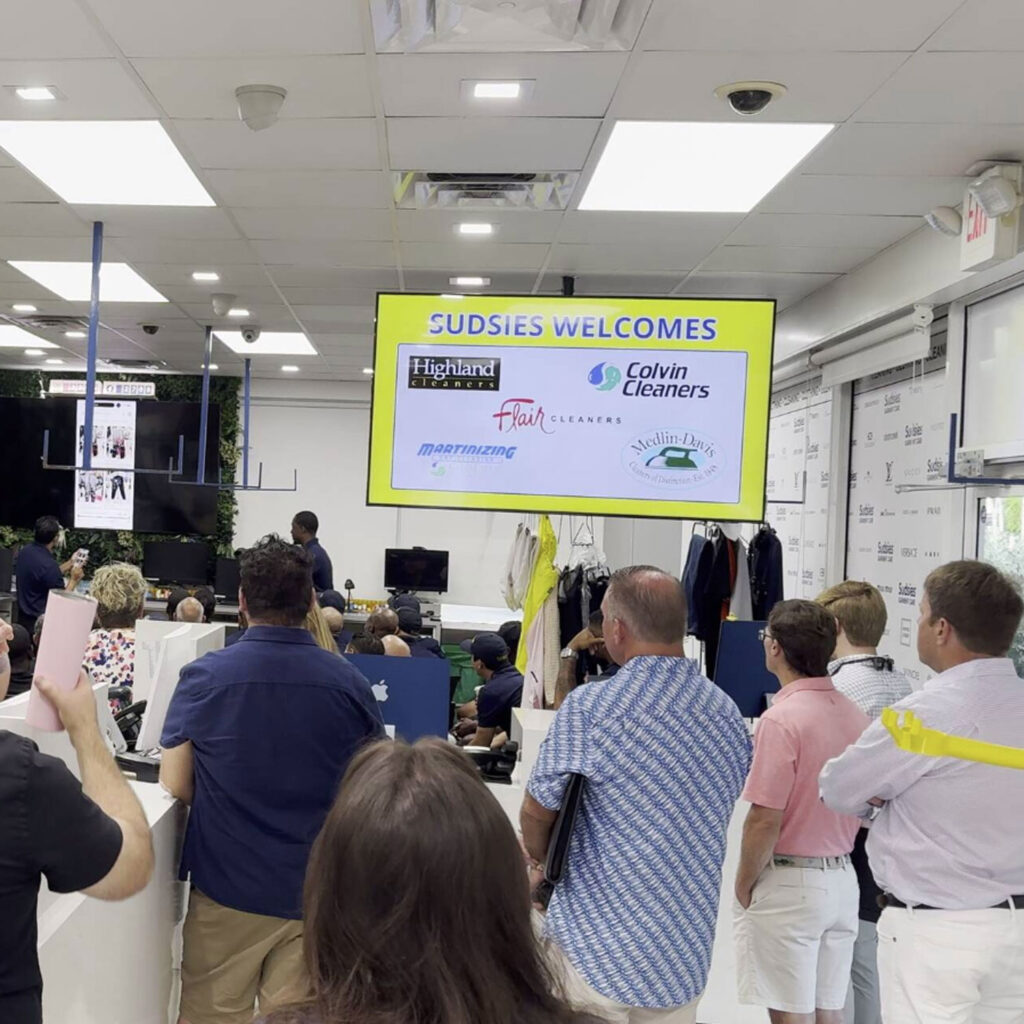 Dry cleaning professionals gathered inside a Sudsies location during an industry meeting