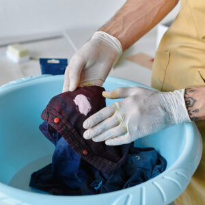 Close-up of hands repairing fabric with a Dy Patch in a blue basin