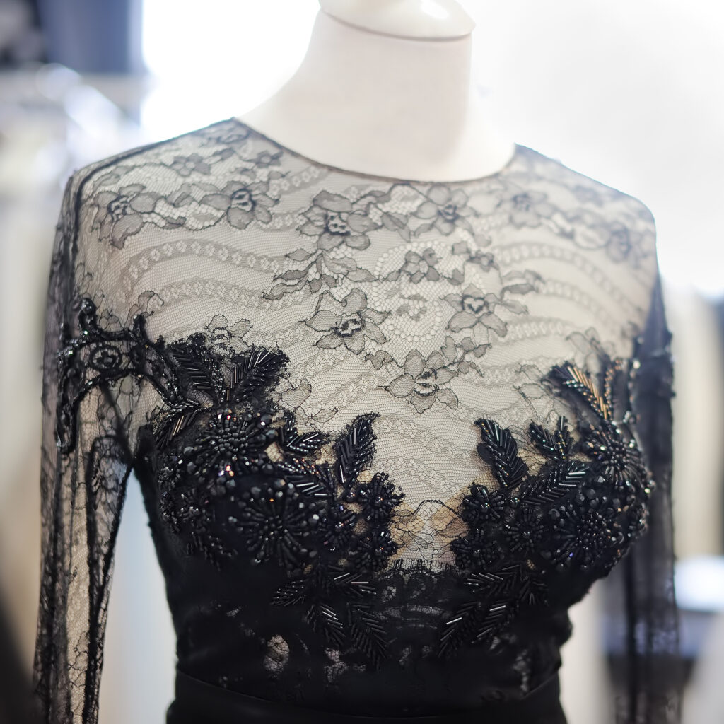 Black silk and lace evening gown with intricate stone embellishments on display