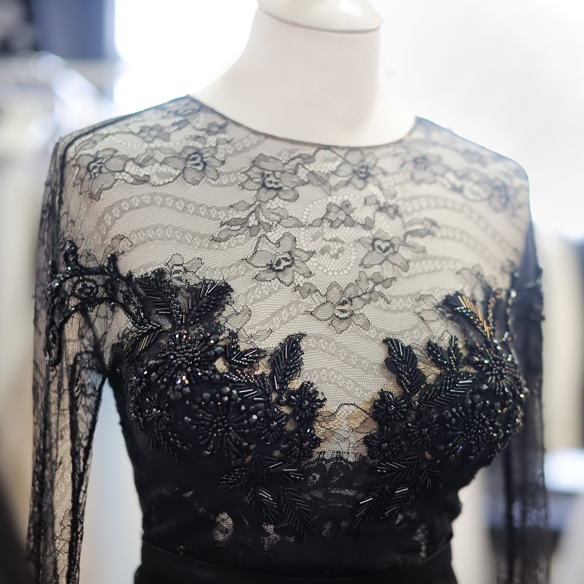 Black silk and lace evening gown with intricate stone embellishments on display