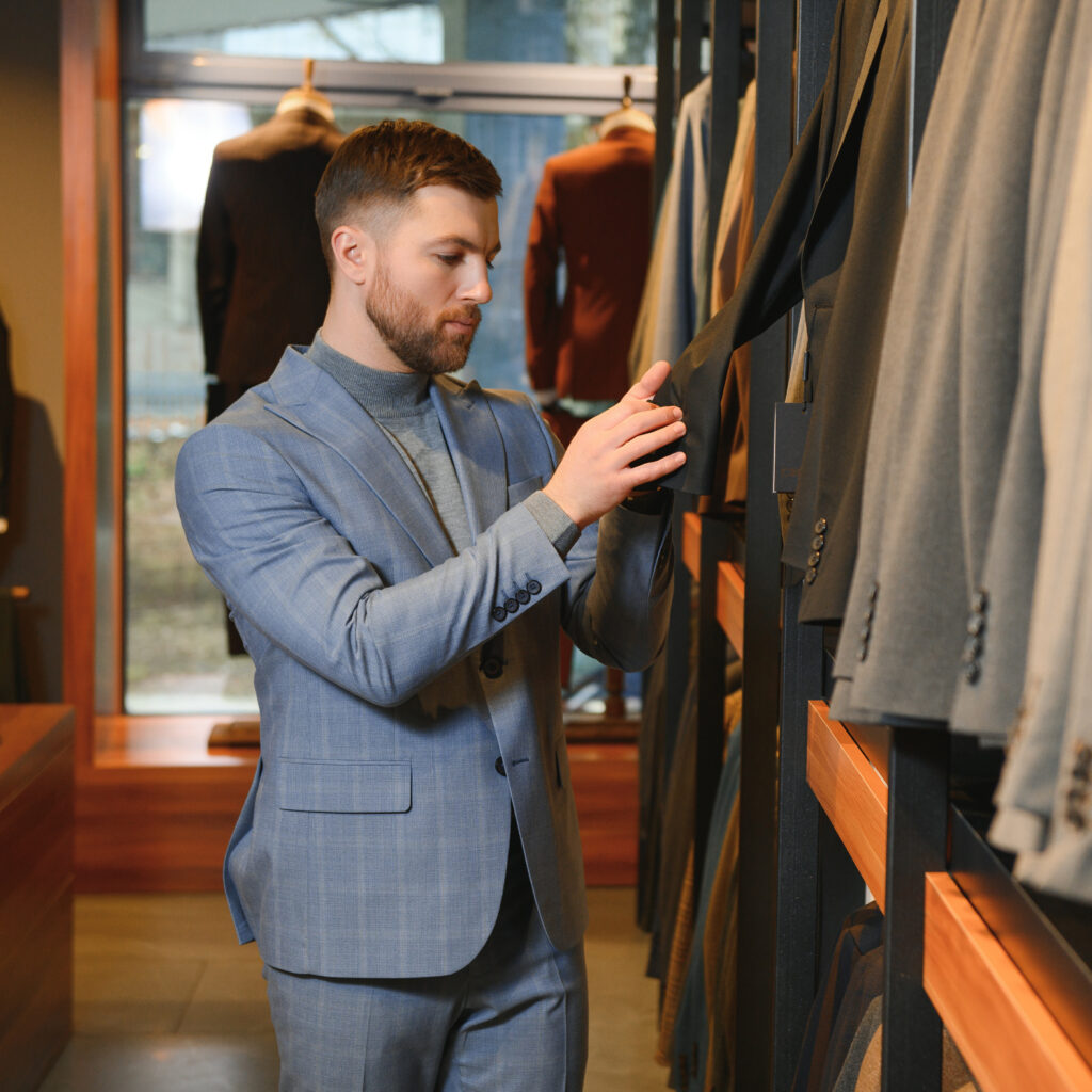 Man in luxury menswear boutique examining a Gucci jacket