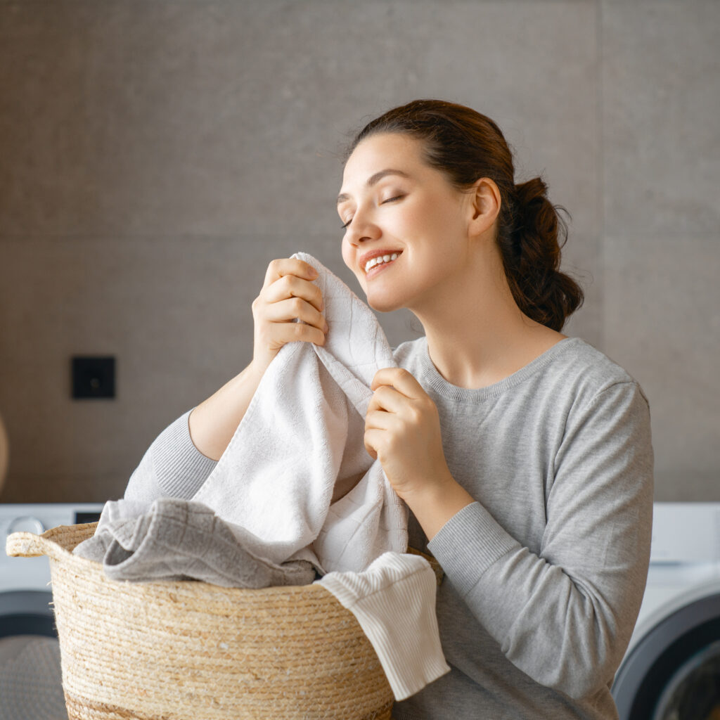 Happy woman enjoying freshly cleaned laundry from Sudsies