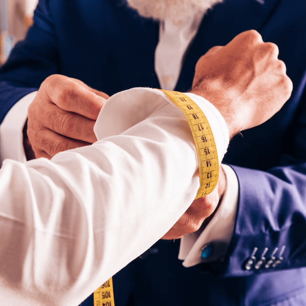 Tailor measuring a client's sleeve for precise garment alterations