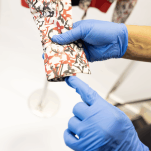 Sudsies expert inspecting couture garment sleeve with blue gloves – luxury dry cleaning and eco-friendly garment care in Miami
