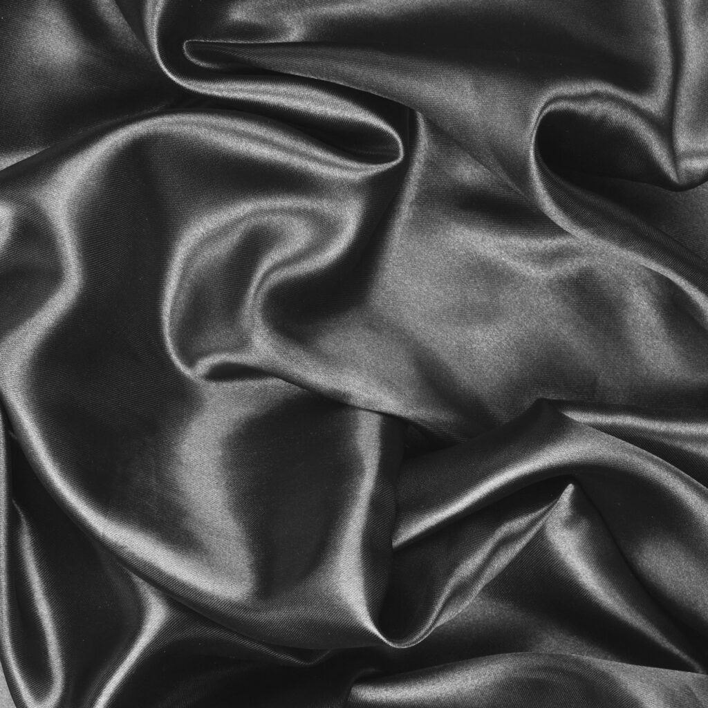 Close-up of black satin fabric with soft folds and sheen