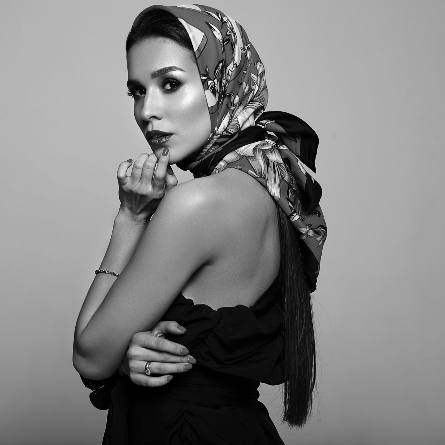 Elegant woman in black-and-white portrait wearing a luxurious printed Hermès-style silk scarf