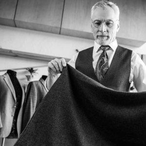 Tailor examining fine fabric in a luxury atelier, reflecting the meticulous craftsmanship of Stefano Ricci