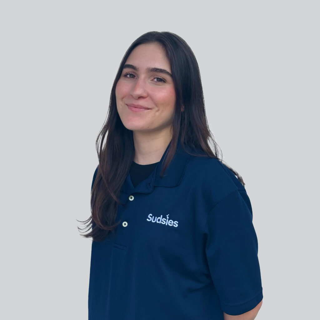 Sami L – Sudsies Team Member Portrait | Sudsies Sami L, a Sudsies team member, smiling in navy blue uniform