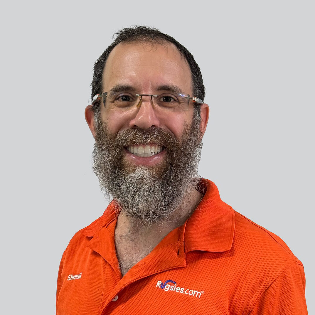 Smiling bearded man in orange RUGSIES polo on grey background