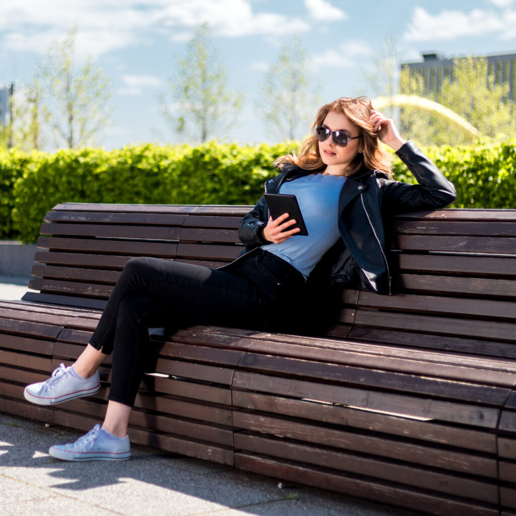 Woman relaxing on bench in Sunny Isles with tablet in hand