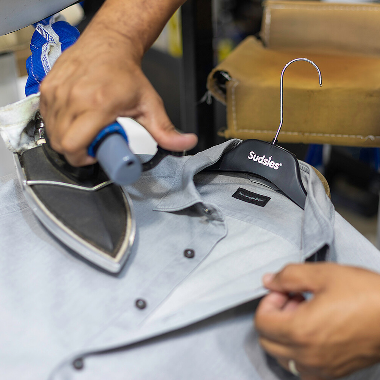 Hand-finishing a luxury dress shirt with precision pressing at Sudsies