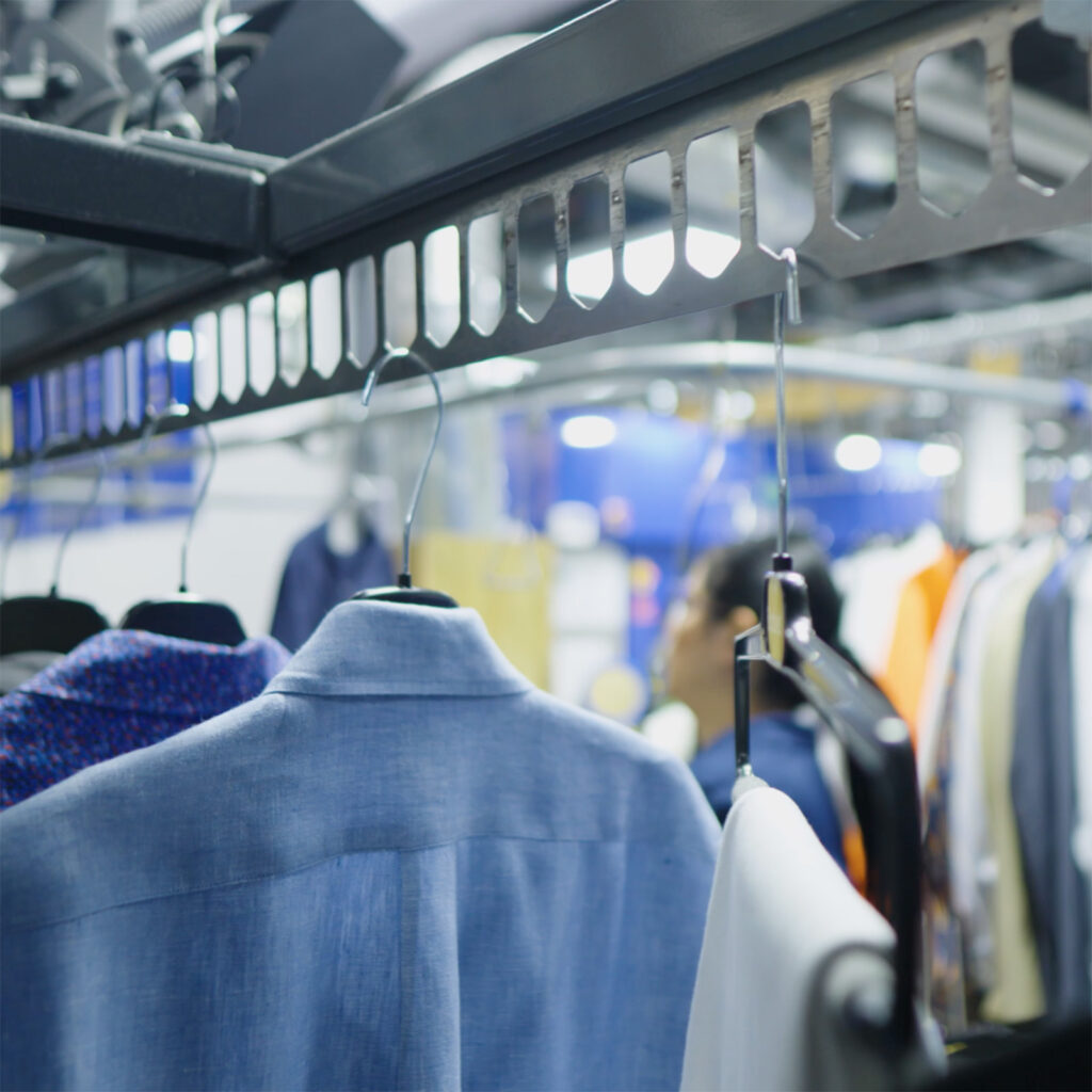 Garments on hangers moving along an automated conveyor rail inside the Sudsies facility