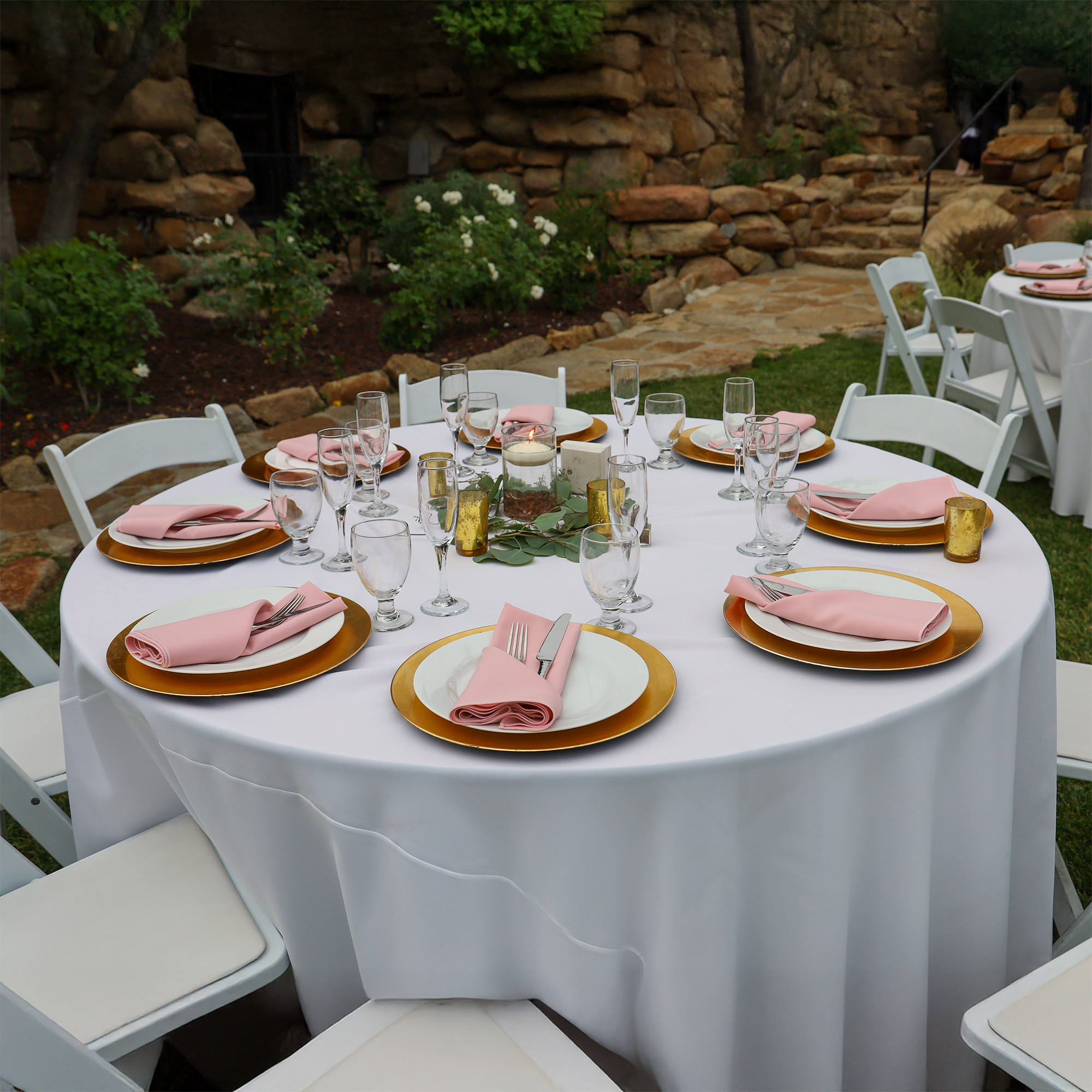 Summer Table Linen Service for Outdoor Events (Crisp & Clean) | Sudsies Outdoor event table set with a white tablecloth, pink napkins, and gold charger plates