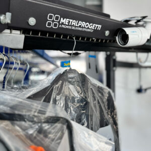 Sudsies garment on conveyor system in protective plastic at the dry cleaning facility