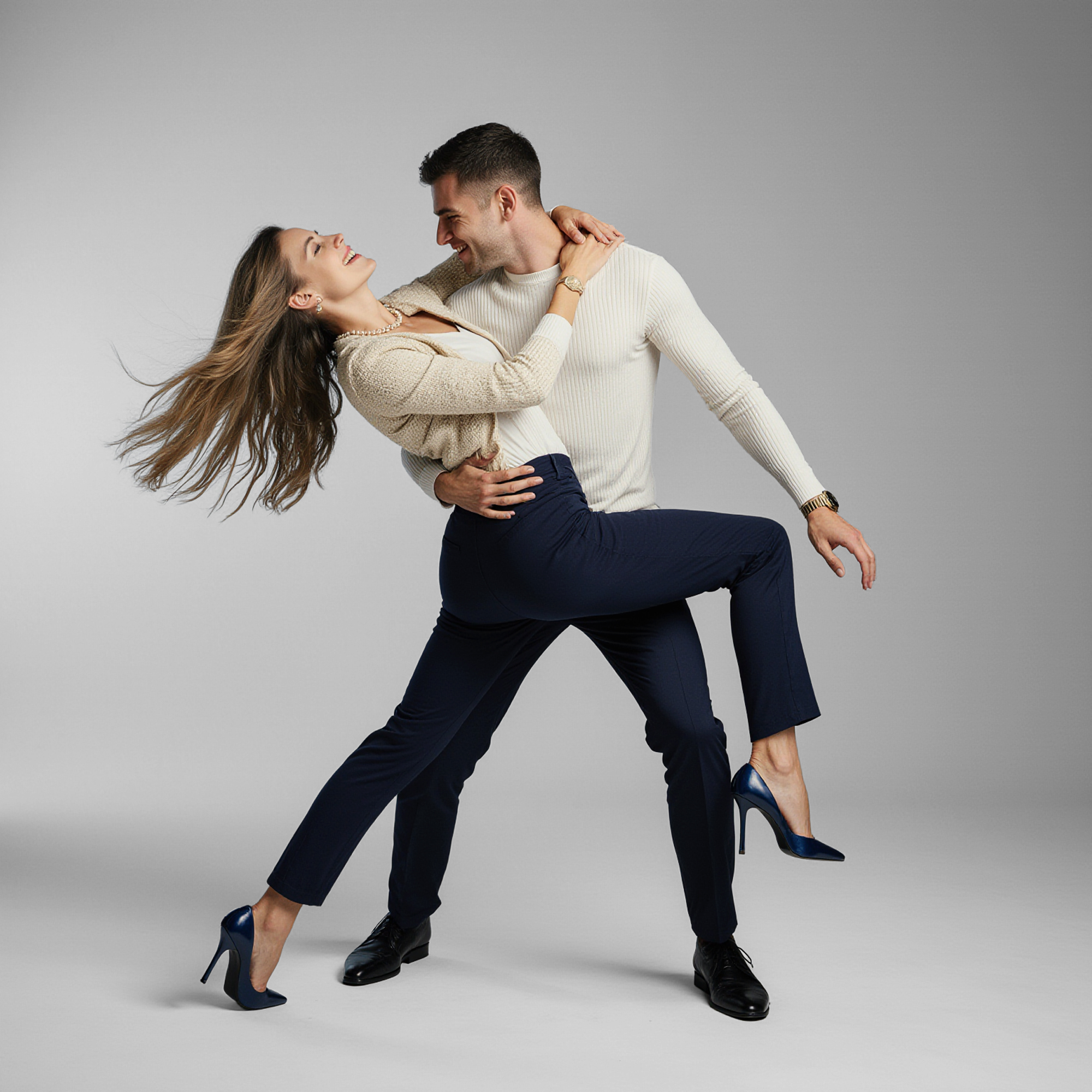 Stylish couple dancing in a studio setting, representing modern luxury lifestyle and premium garment care