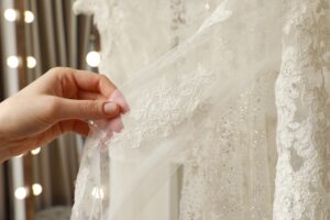 Young woman choosing wedding dress in salon closeup | Sudsies