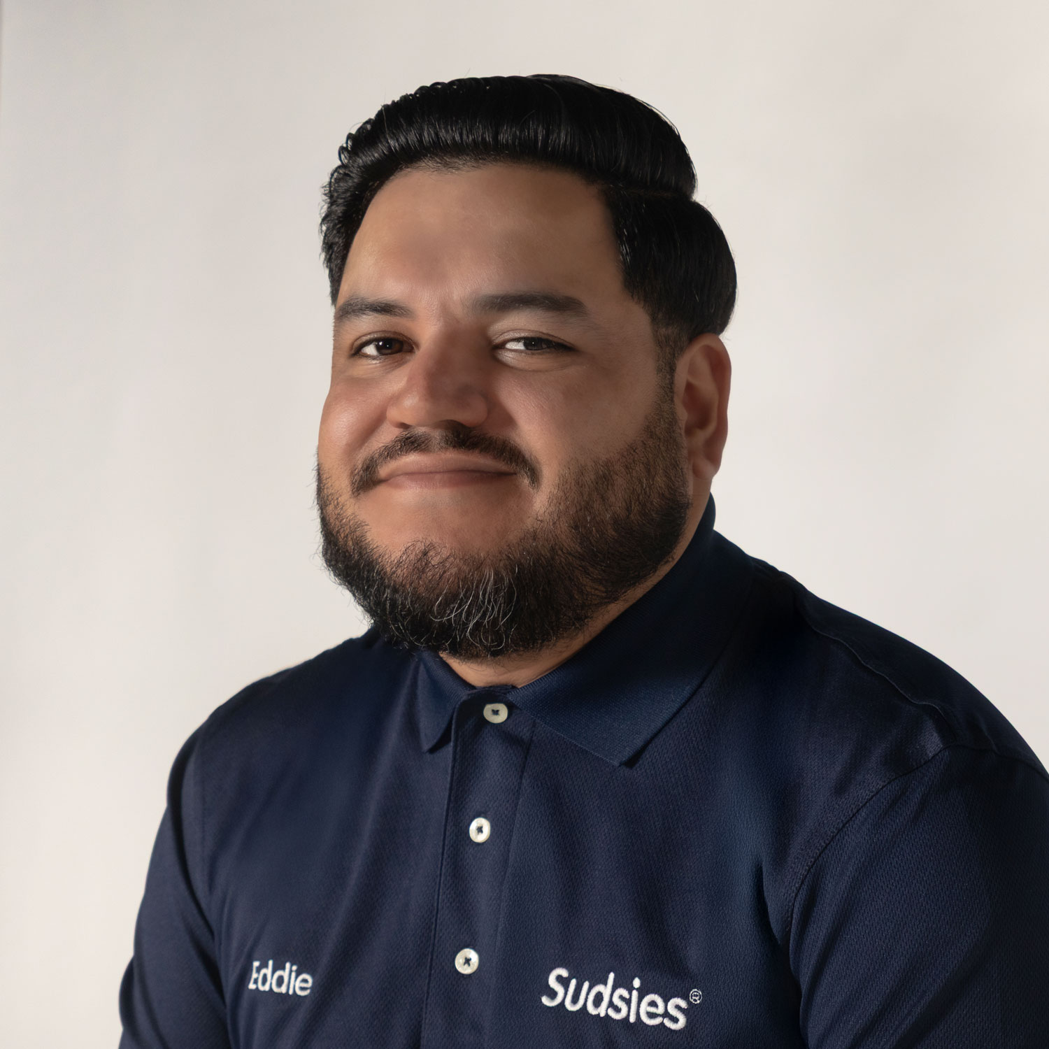 Eduardo Perez, Human Resources Manager at Sudsies, wearing a navy Sudsies polo in a professional studio headshot