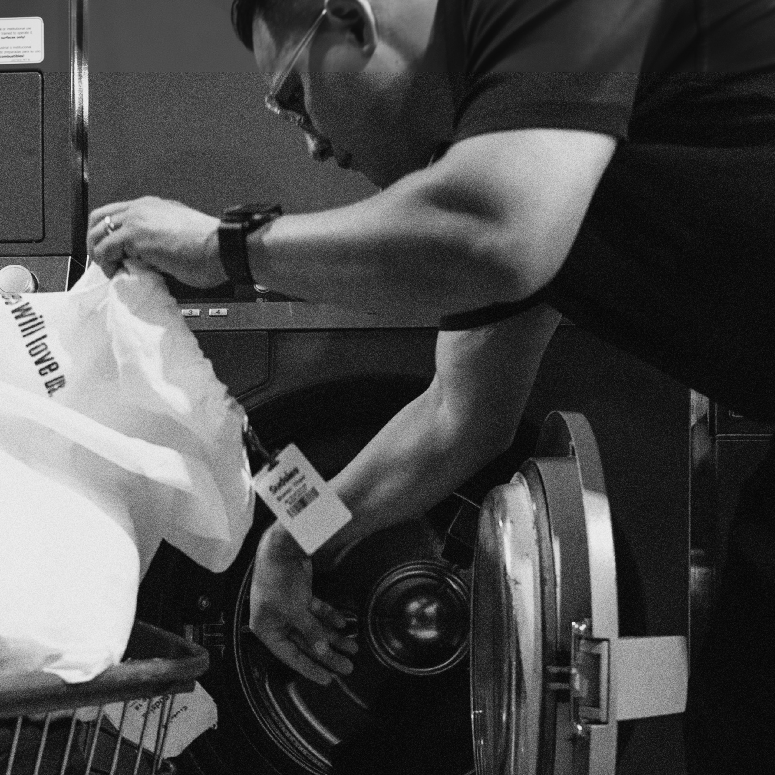Sudsies team member placing a tagged white garment into a professional cleaning machine