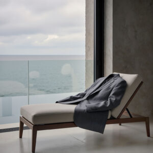 Freshly cleaned suit resting on lounge chair overlooking ocean, representing Sudsies garment care