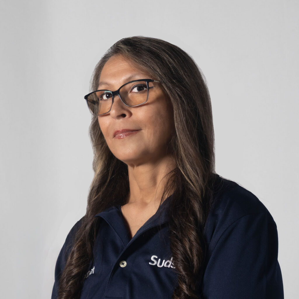 Portrait of a woman with long dark hair and glasses wearing a navy polo shirt.