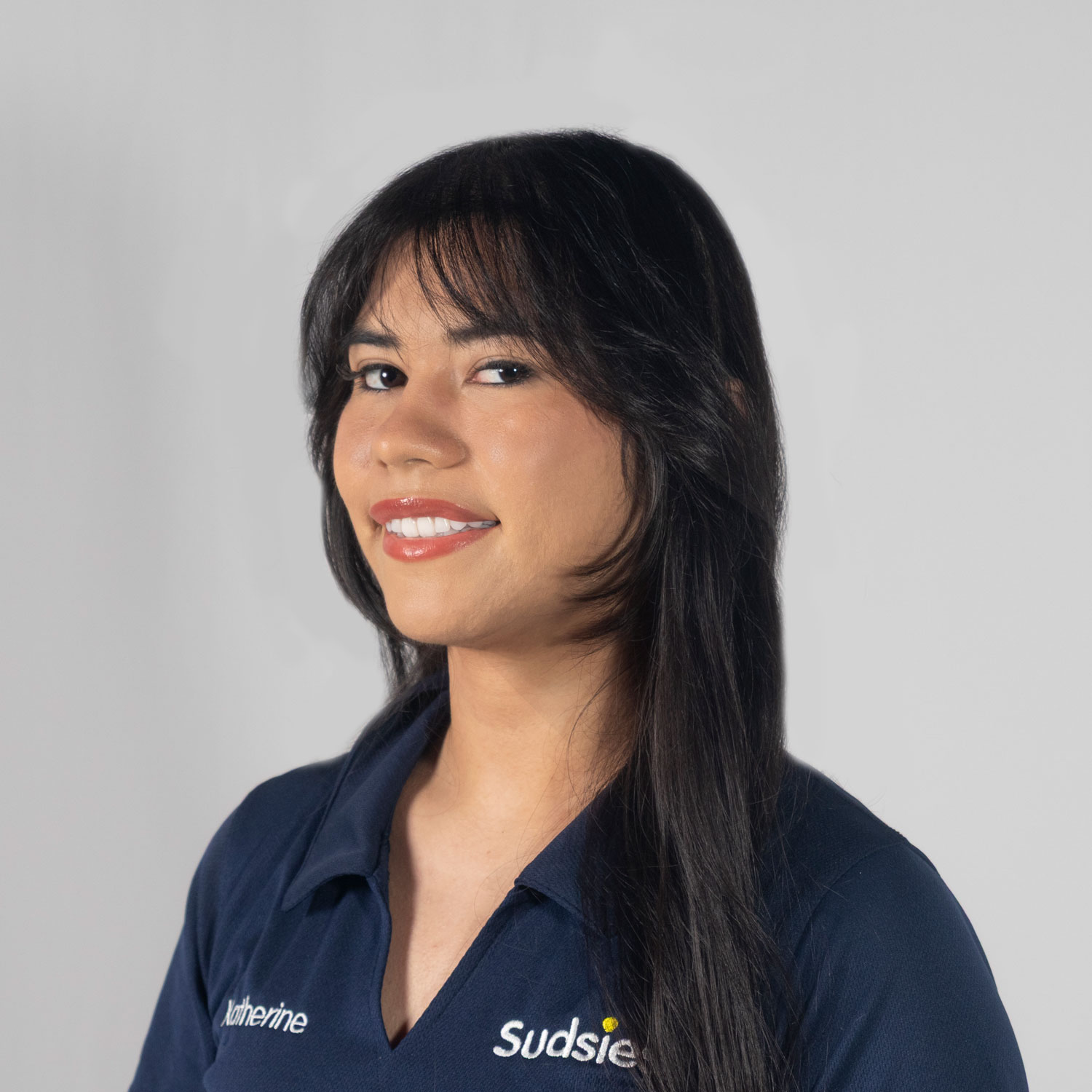 Portrait of a smiling woman with long dark hair in a navy polo shirt, facing slightly left.