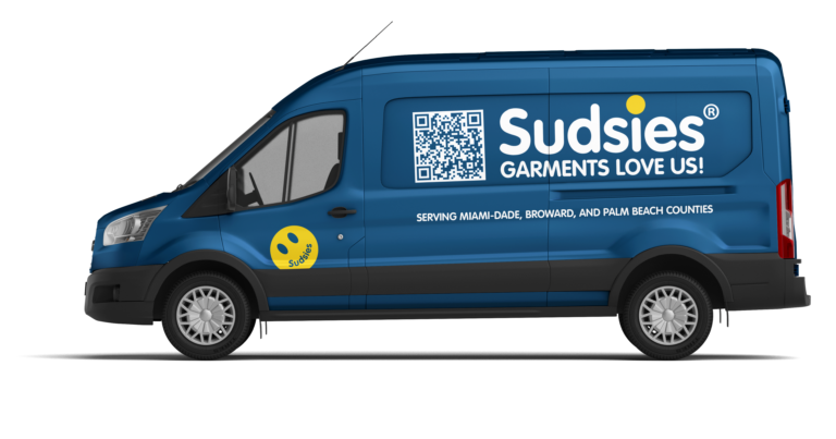 Blue Sudsies branded cargo van shown from the side with a large QR code, white logo, and the slogan'GARMENTS LOVE US!' along the side.