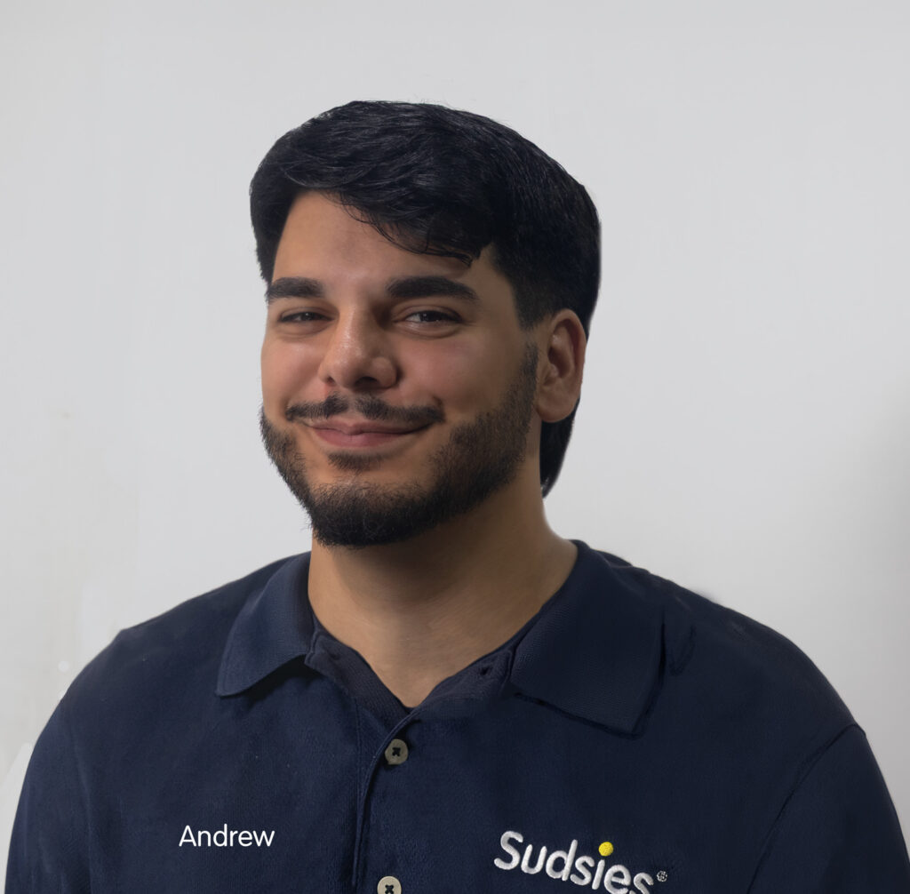 Portrait of Andrew, a Sudsies Customer Service Representative, wearing a navy Sudsies uniform in a studio setting.