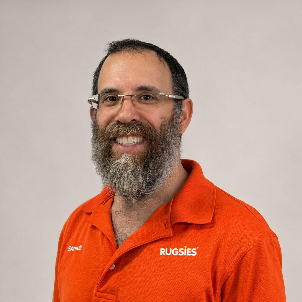 Portrait of Schmuli Rudski, Textile Cleaning Specialist at Rugsies, wearing an orange Rugsies polo in a studio setting.